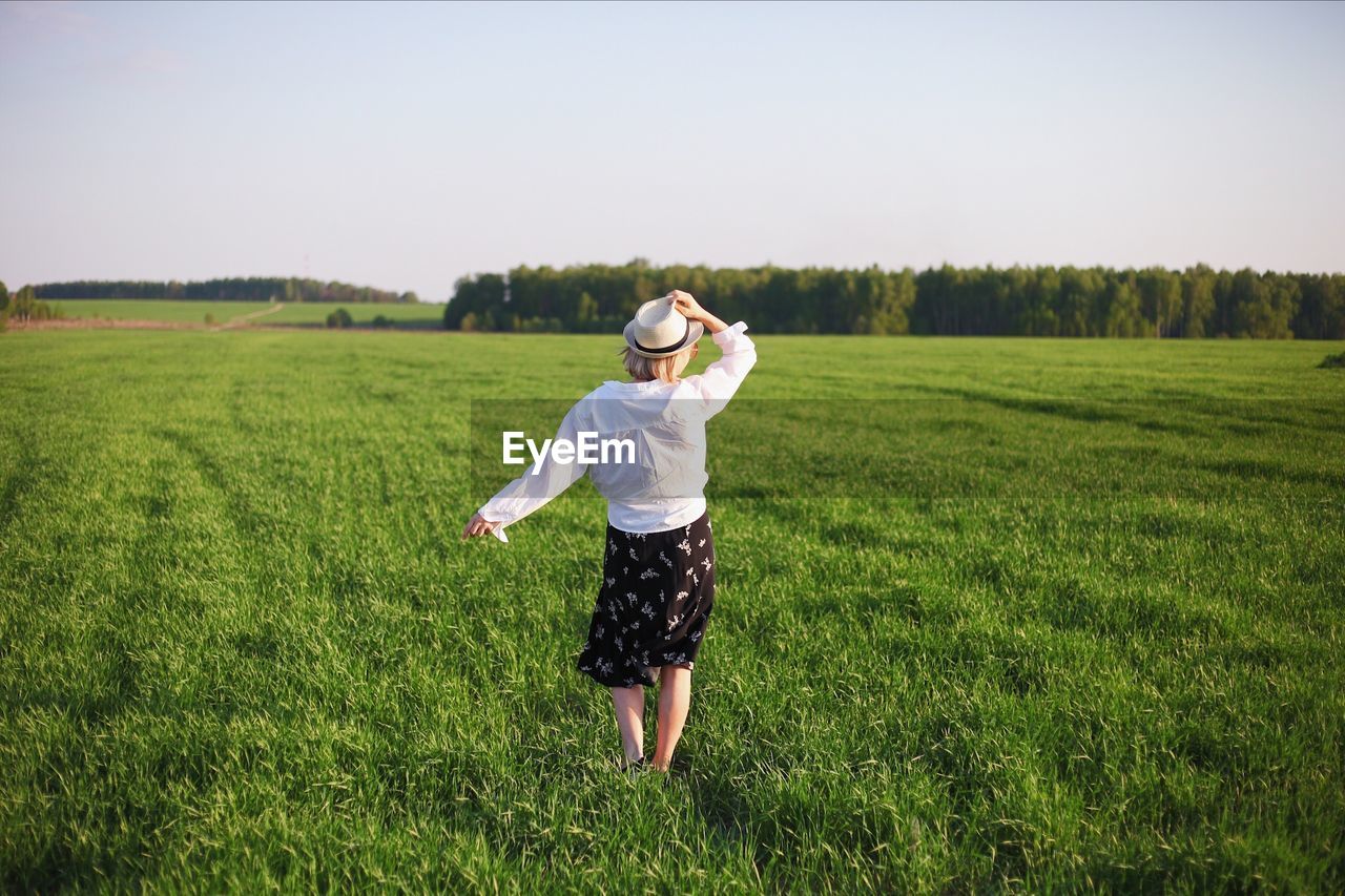 Rear view of woman standing on grassy land