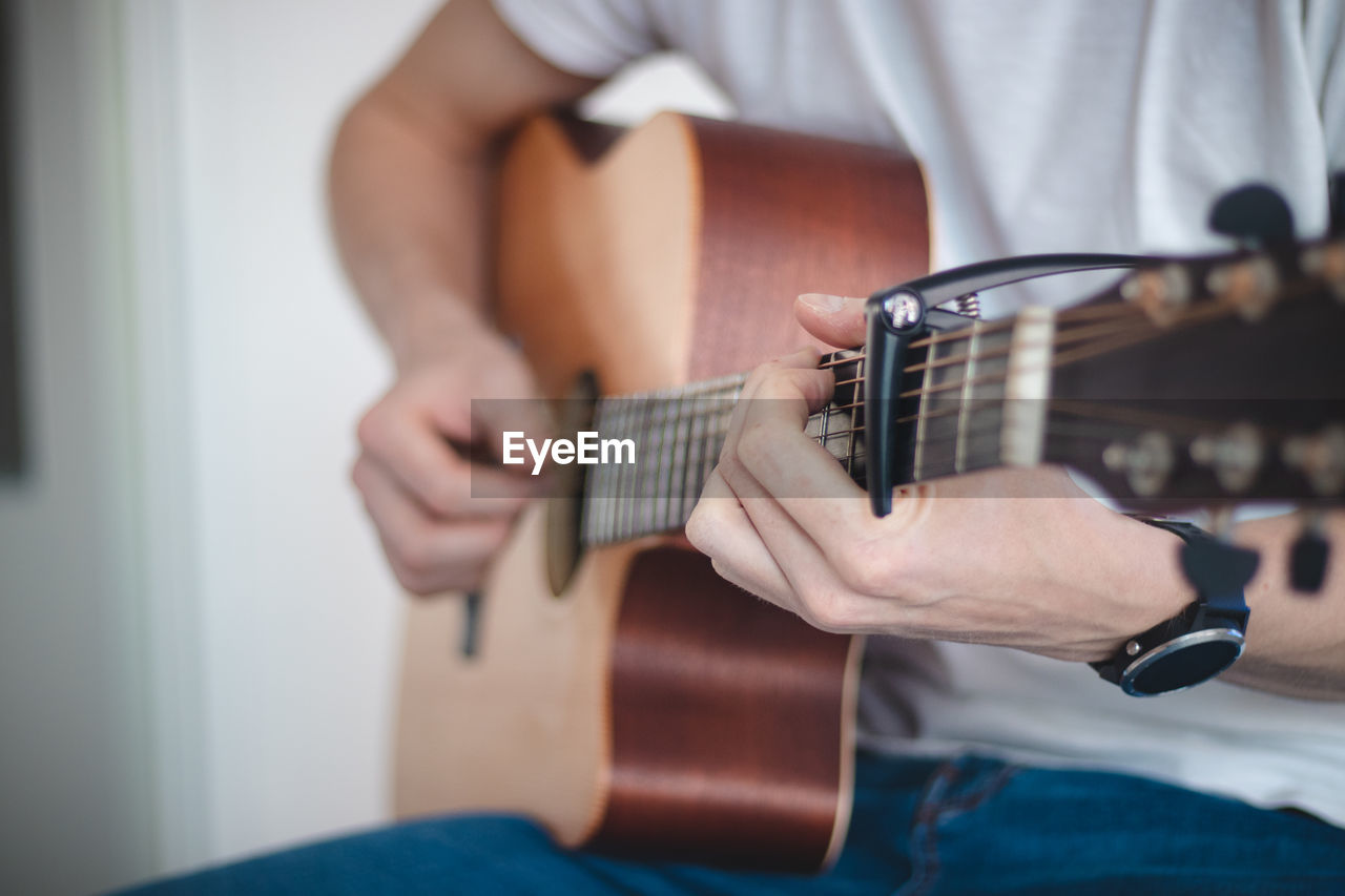 Midsection of man playing guitar