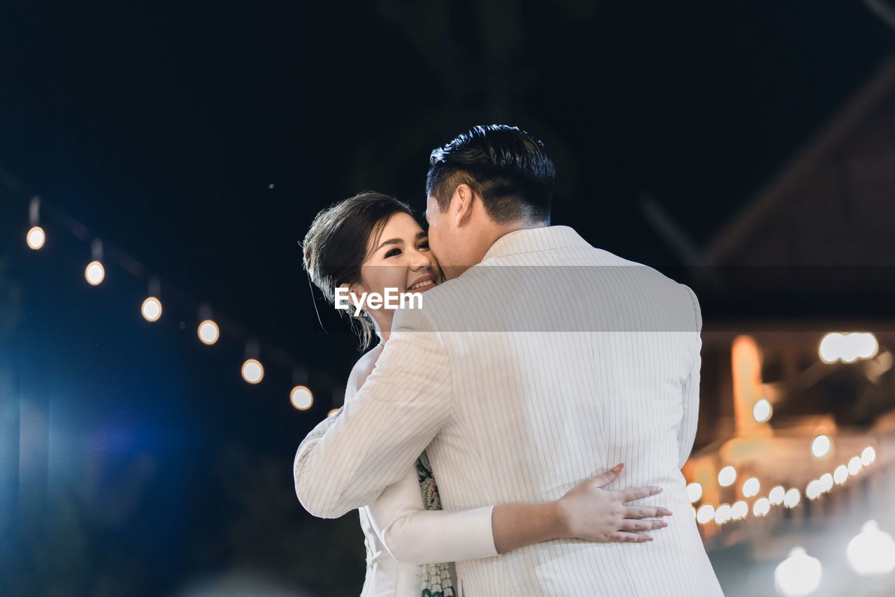 Young couple standing outdoors at night