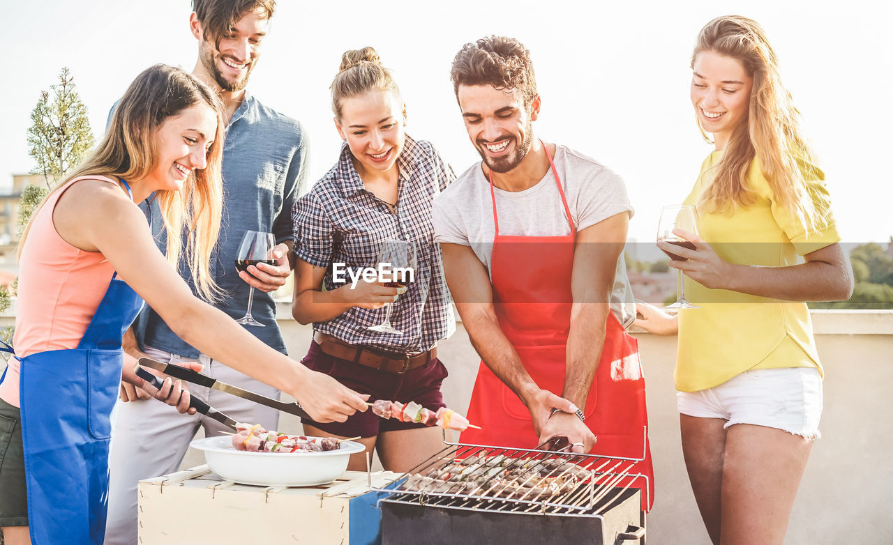 Happy friends preparing food on barbecue