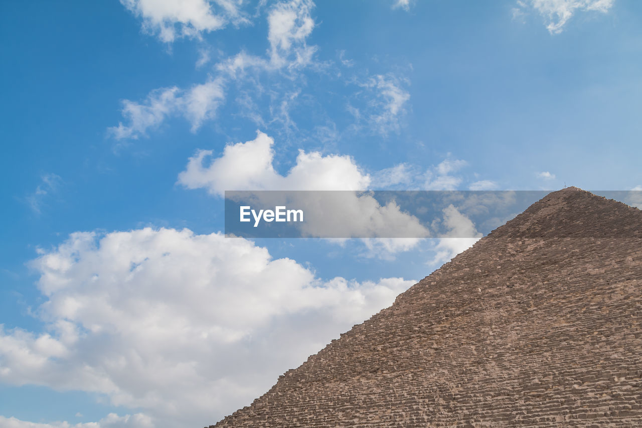 Low angle view of pyramid against cloudy sky