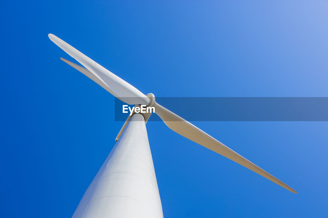 Wind turbine against blue sky from low angle