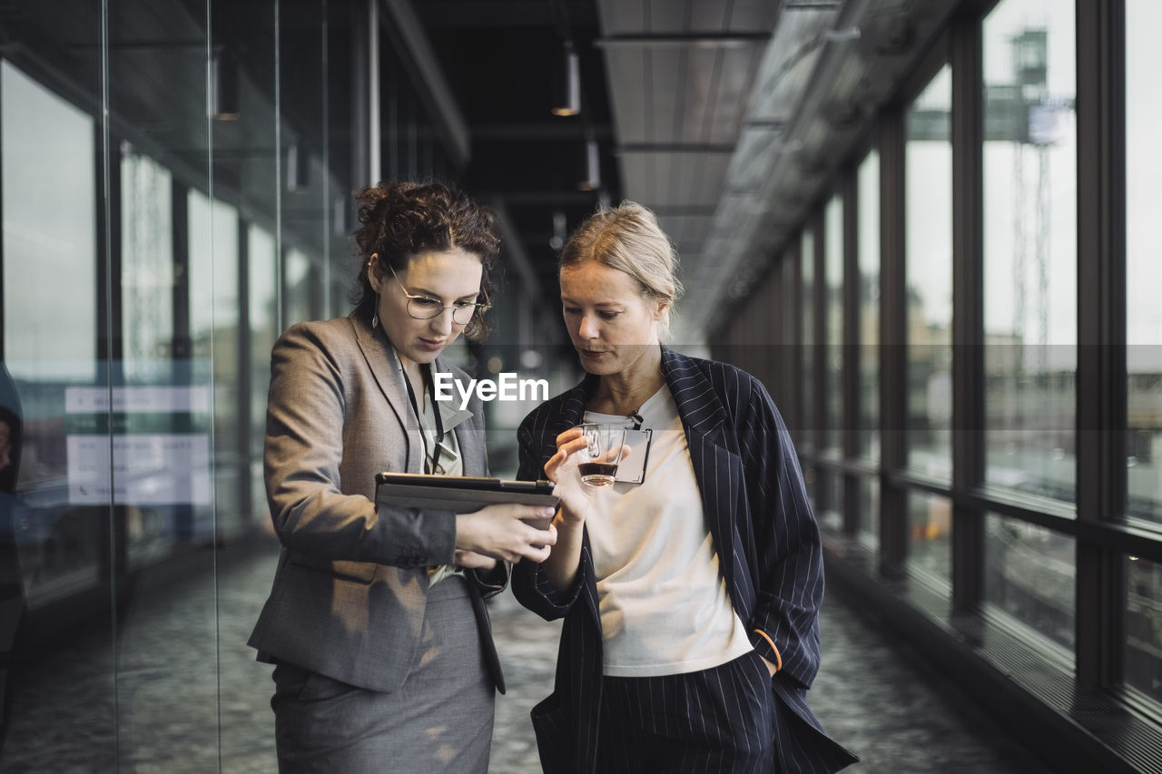 Female business professionals discussing in corridor at workplace