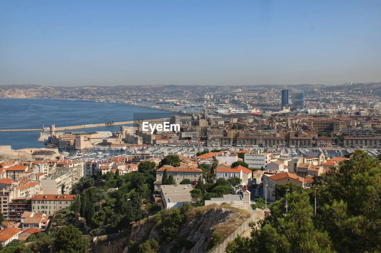 High angle view of townscape by sea against clear sky