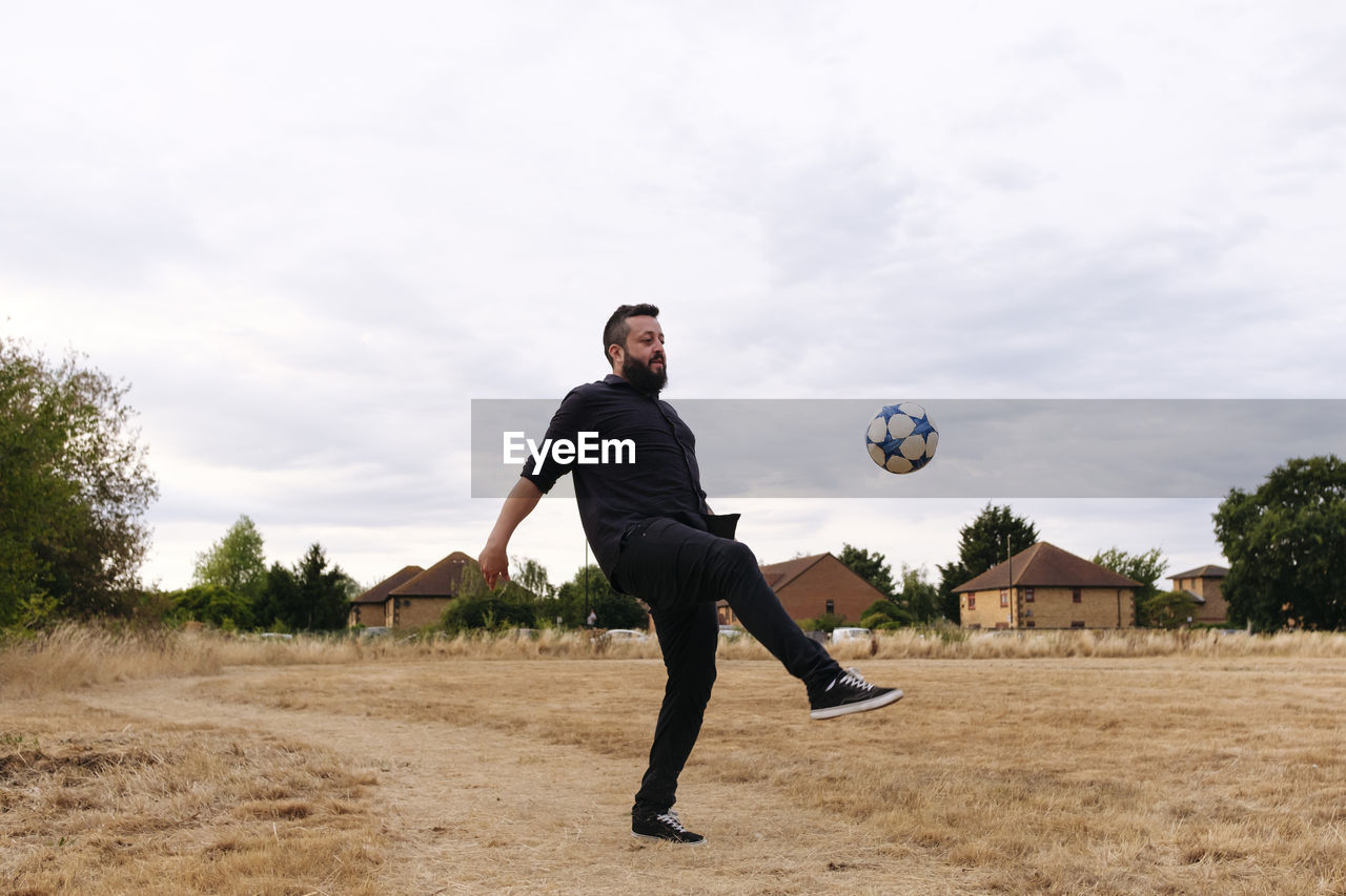 Mature man playing with soccer ball in field
