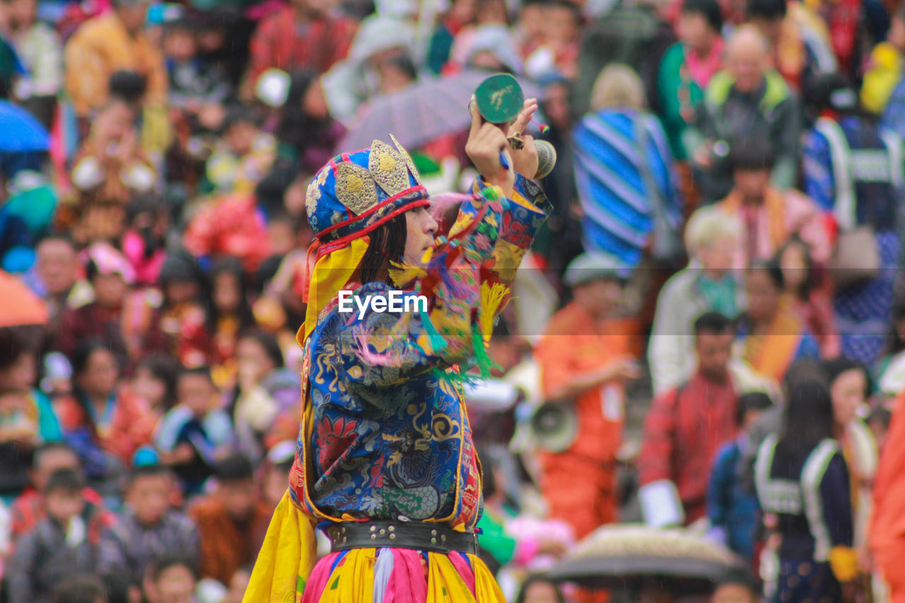 Side view of male artist in colorful traditional clothing performing against audience