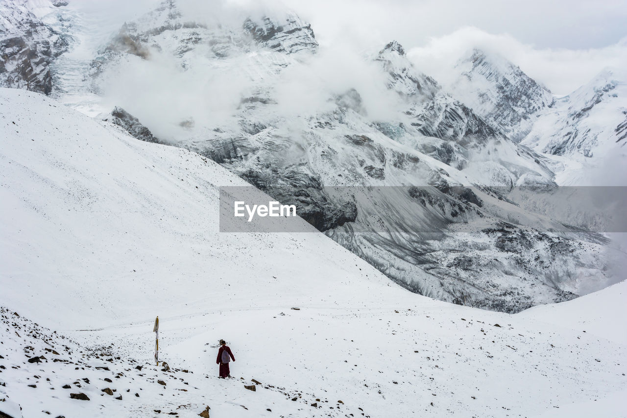 Rear view of person walking on snow covered mountain