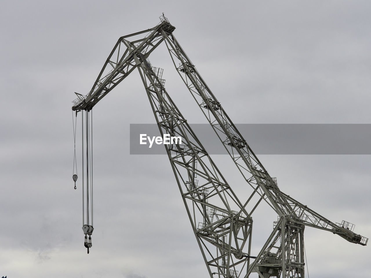 Low angle view of crane at construction site against sky