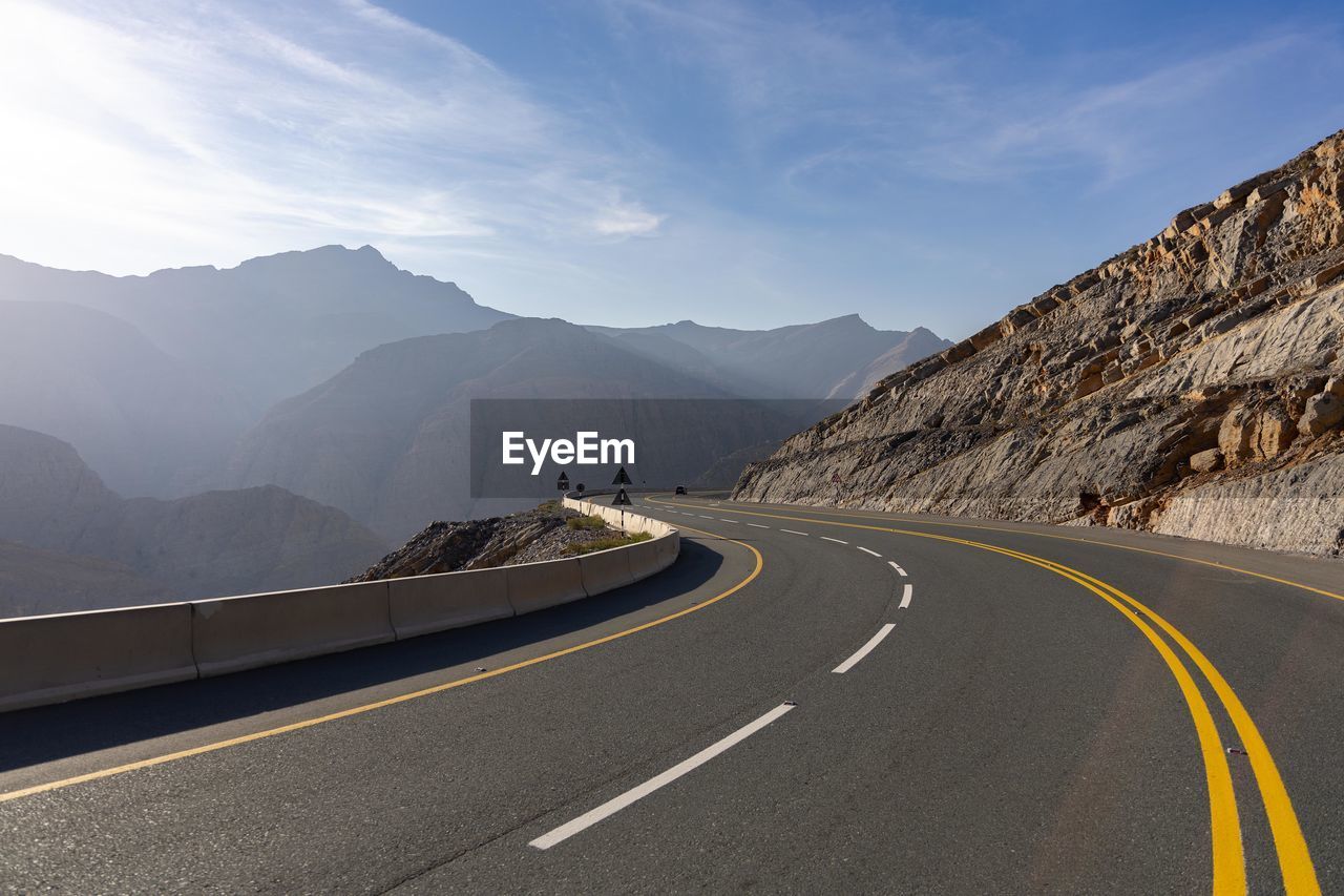 scenic view of road by mountains against sky