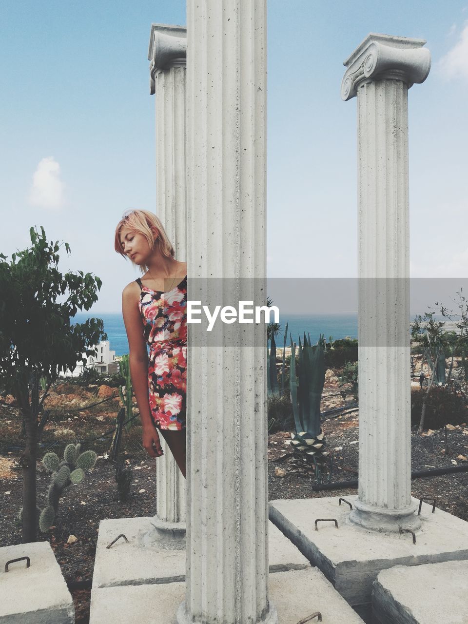 Young woman standing by architectural columns
