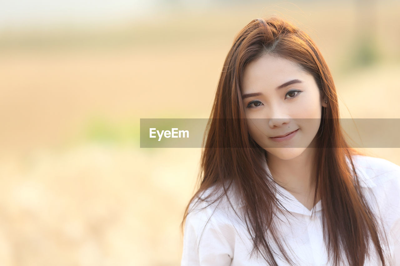 Portrait of beautiful young woman standing on field