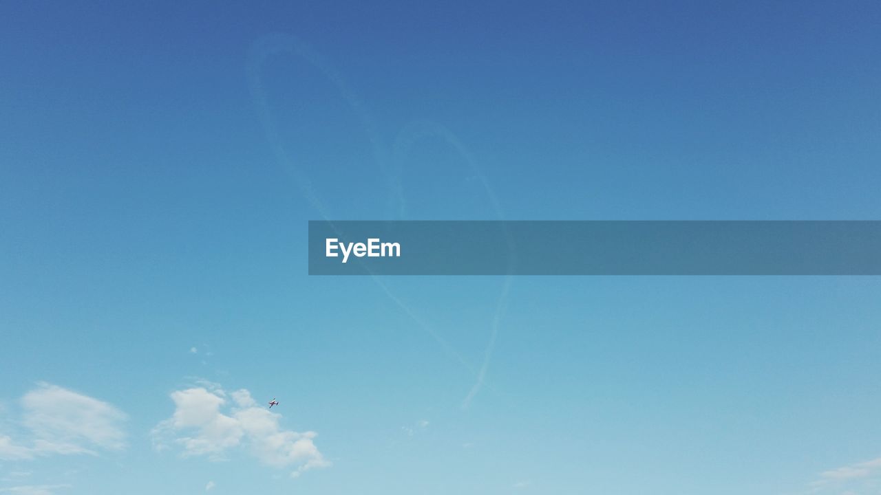 LOW ANGLE VIEW OF VAPOR TRAILS IN BLUE SKY