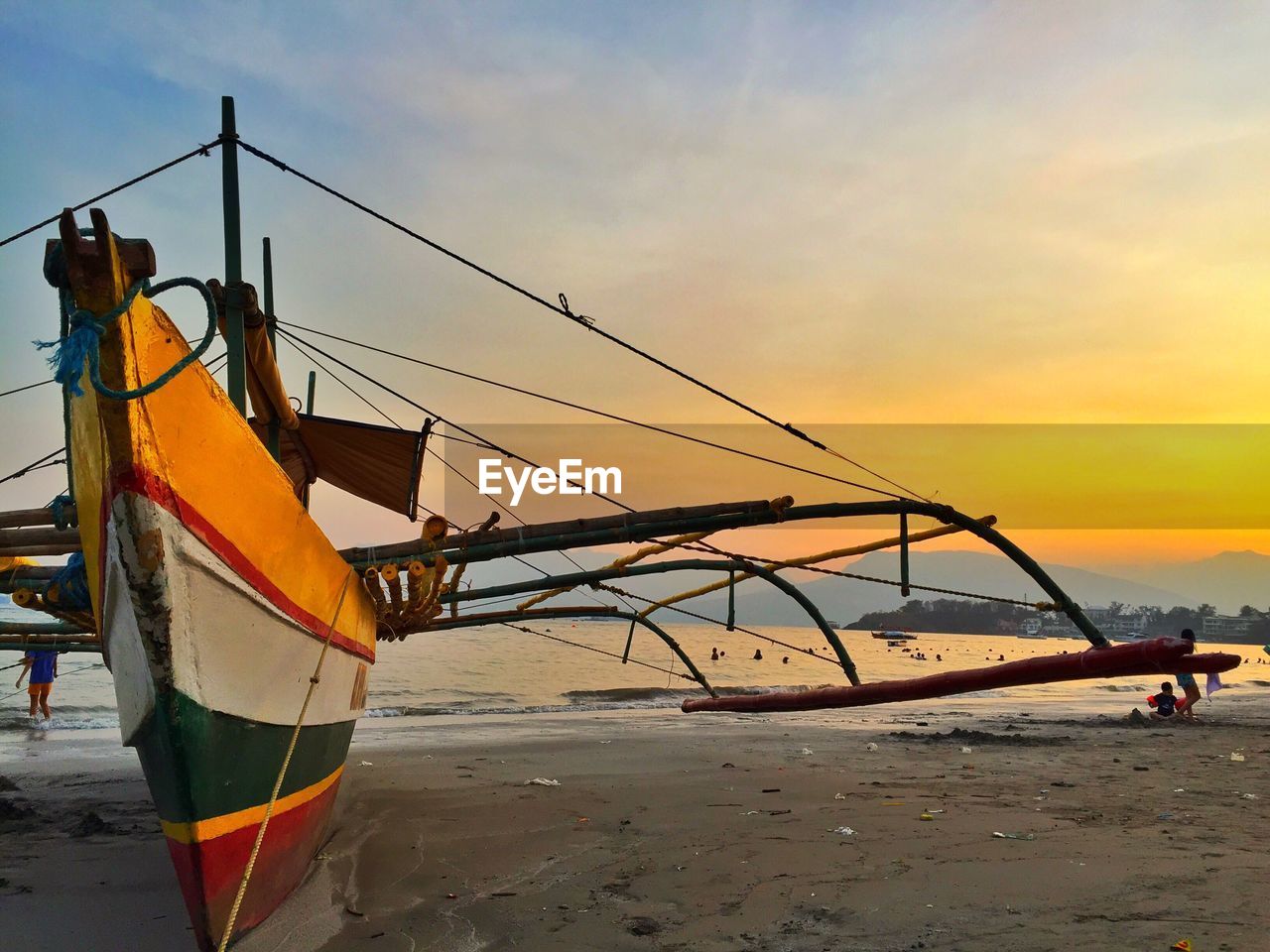 Ship moored on beach against sky during sunset