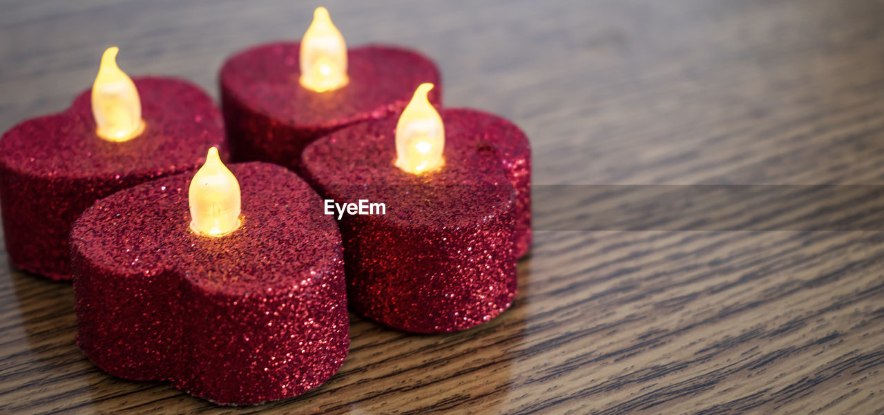 CLOSE-UP OF BURNING CANDLES ON TABLE