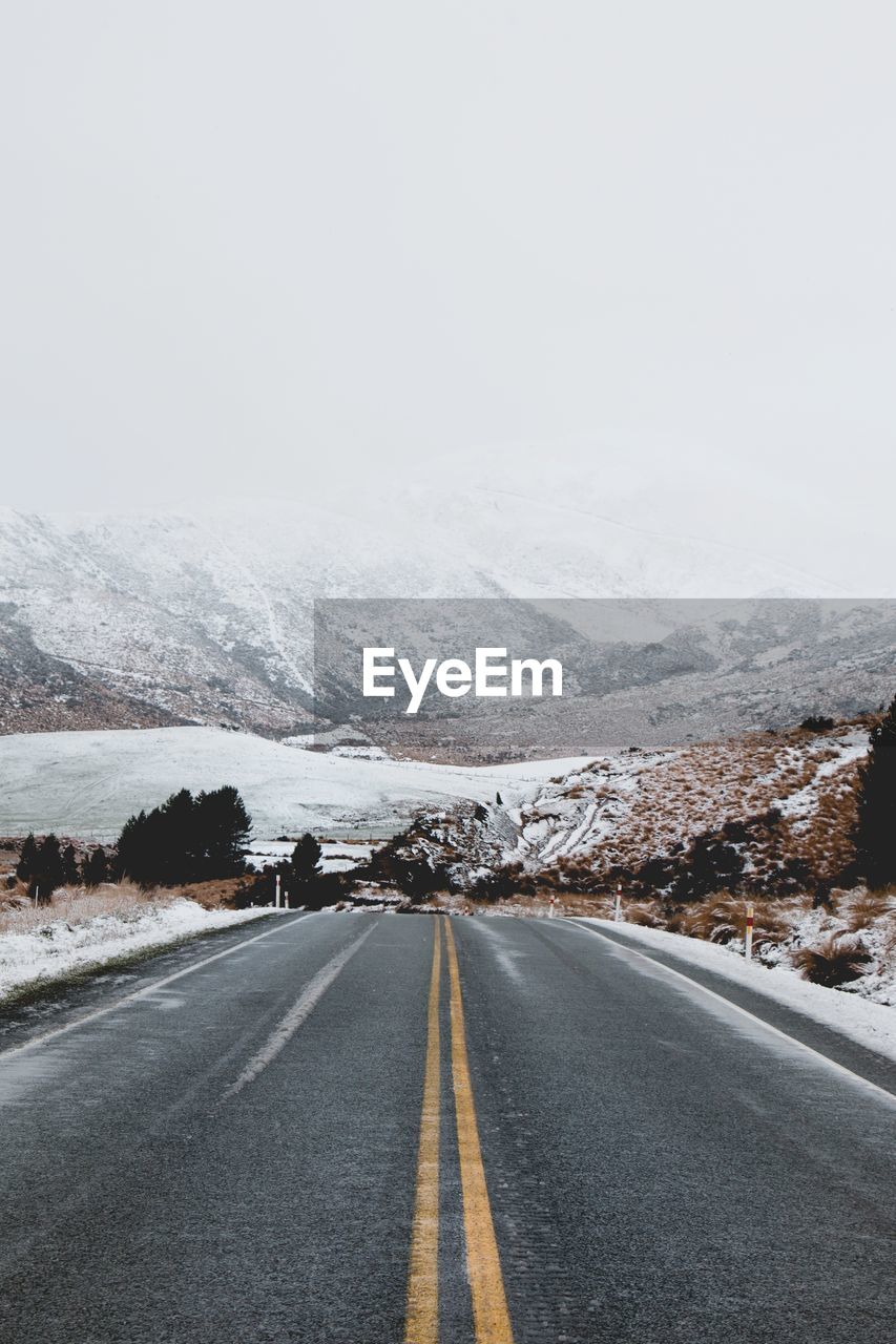 ROAD BY SNOWCAPPED MOUNTAIN AGAINST SKY DURING WINTER