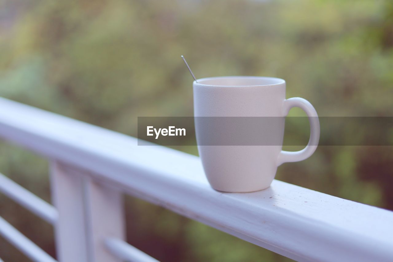 CLOSE-UP OF COFFEE CUP ON RAILING