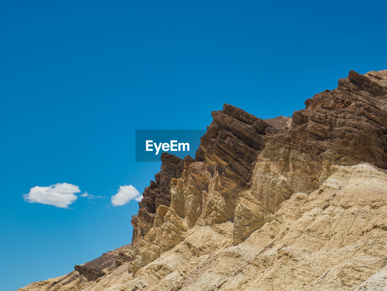 LOW ANGLE VIEW OF ROCK FORMATION AGAINST BLUE SKY