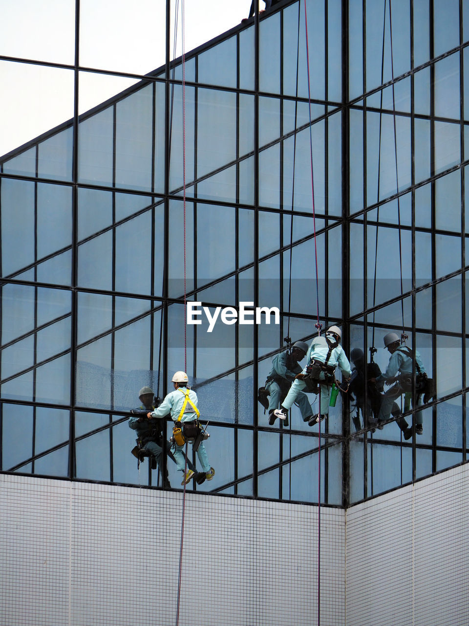 Low angle view of window washers working on modern building