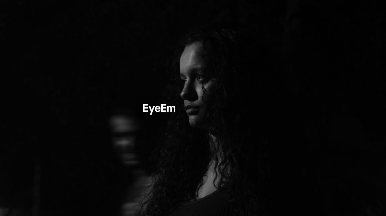 Close-up of young woman against black background