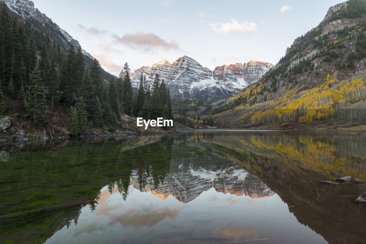 The snowy maroon bells reflected in the maroon lake at sunrise in the fall, aspen, colorado