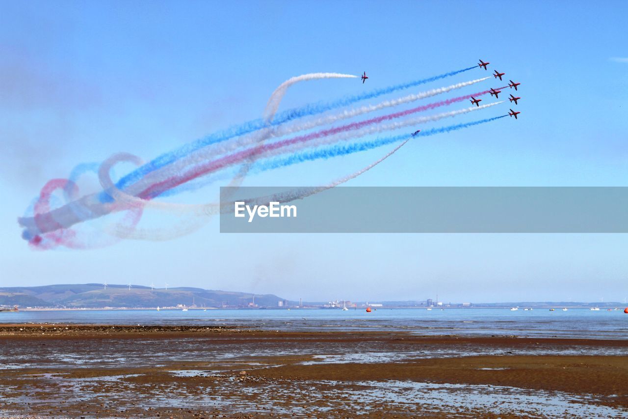 AIRPLANE FLYING OVER SEA AGAINST VAPOR TRAIL