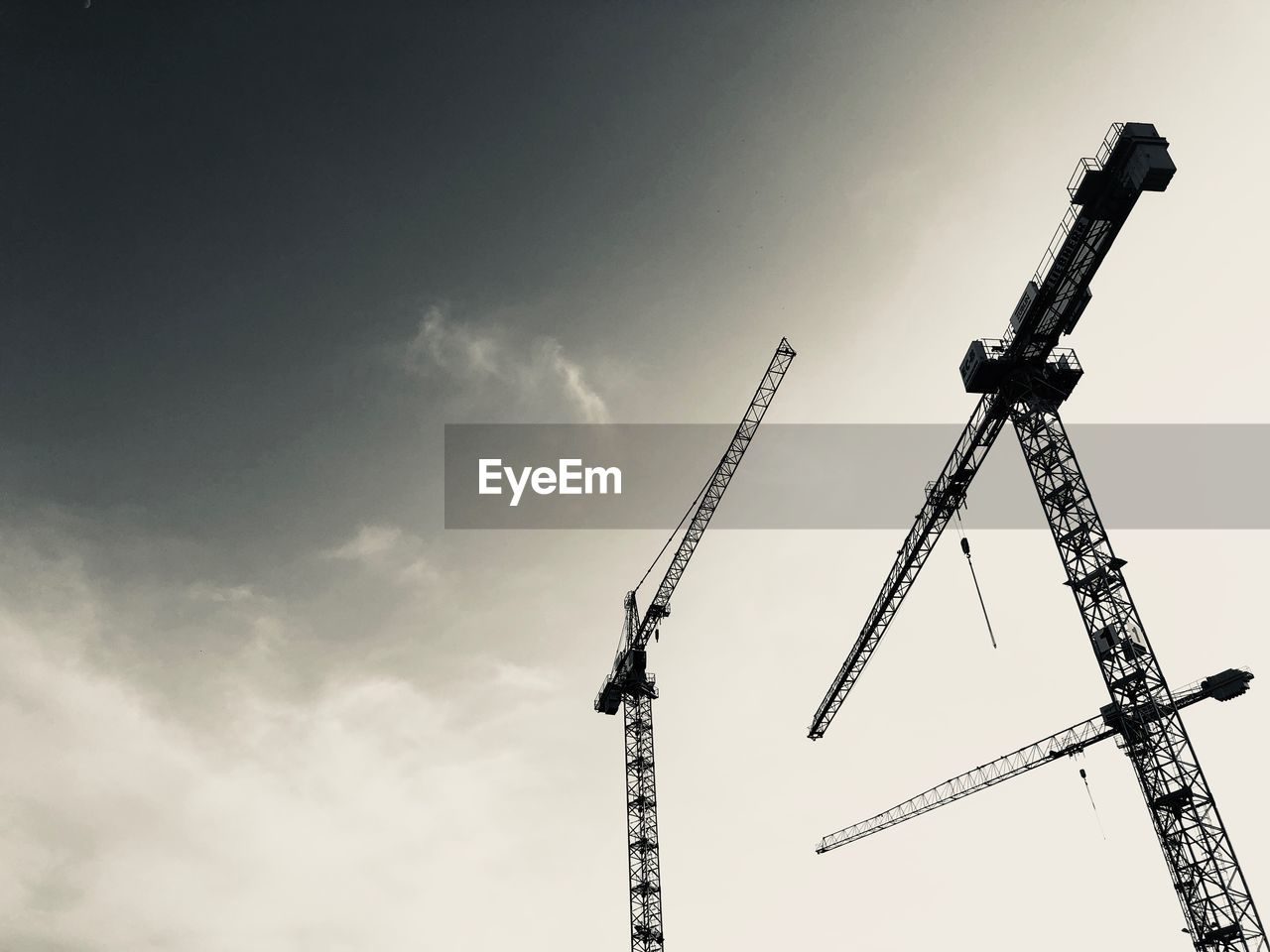 Low angle view of cranes against sky