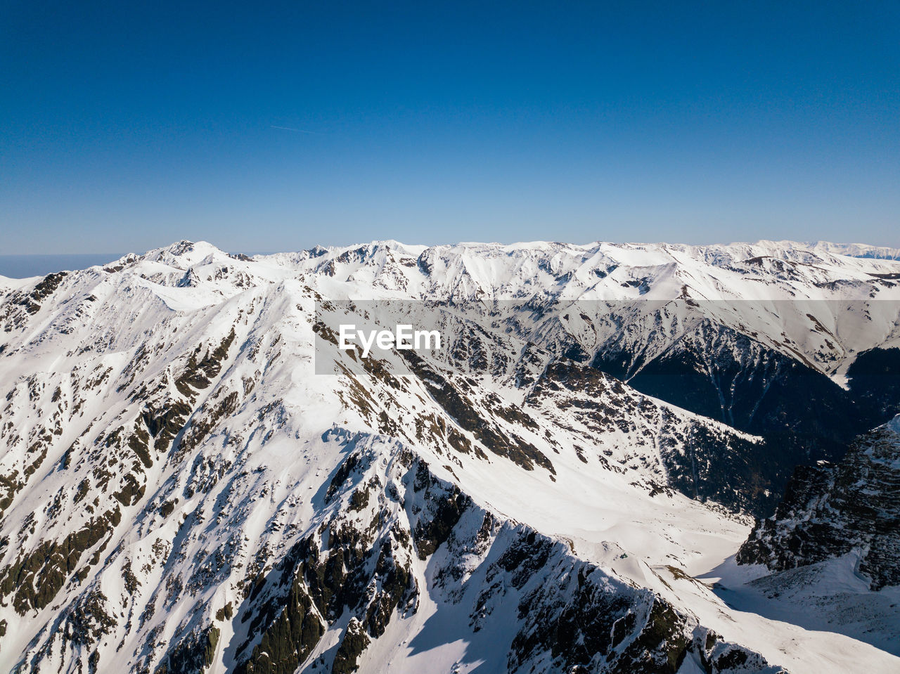 Scenic view of snowcapped mountains against clear blue sky