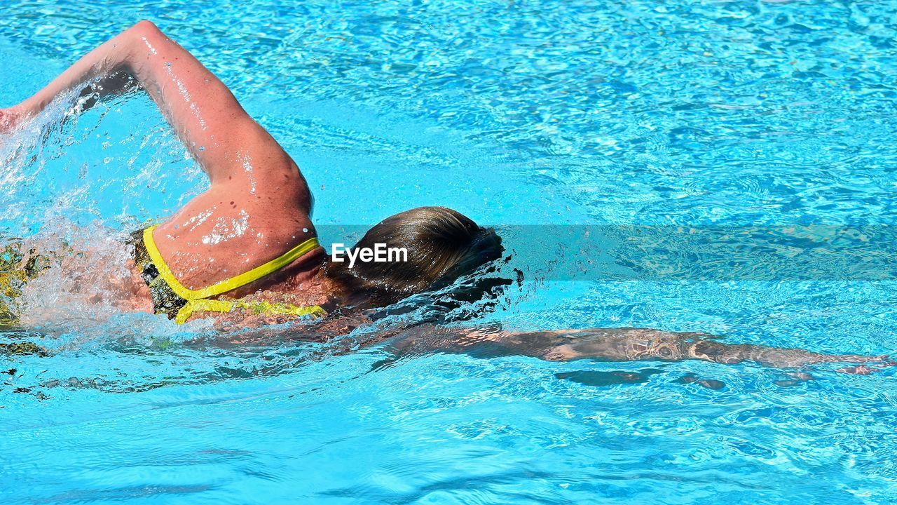 Woman swimming in pool on sunny day