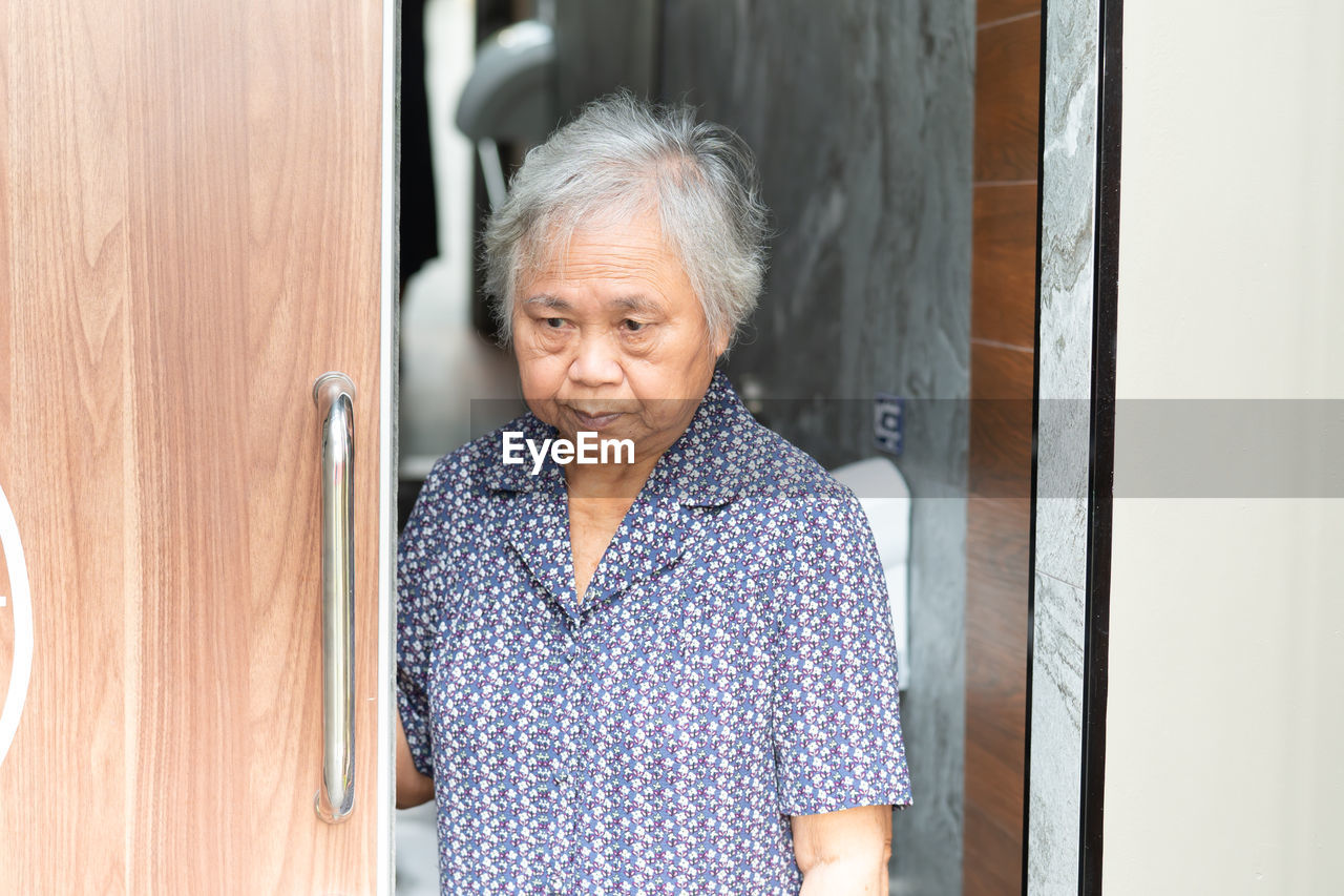 Portrait of woman standing against door at home