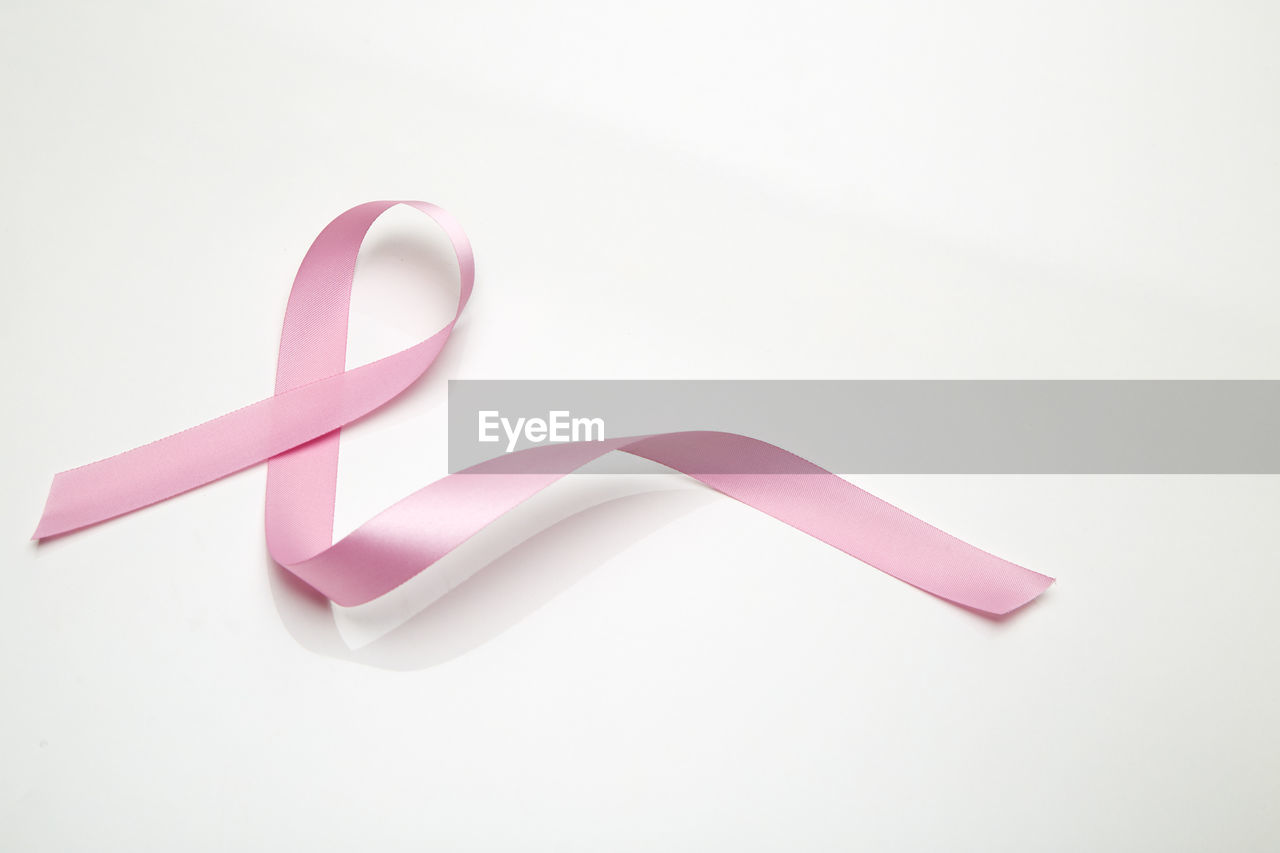 Close-up of breast cancer awareness ribbon over white background