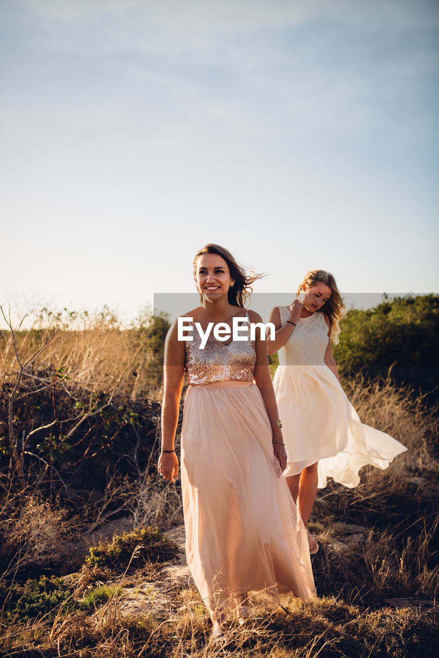 Young women standing against sky