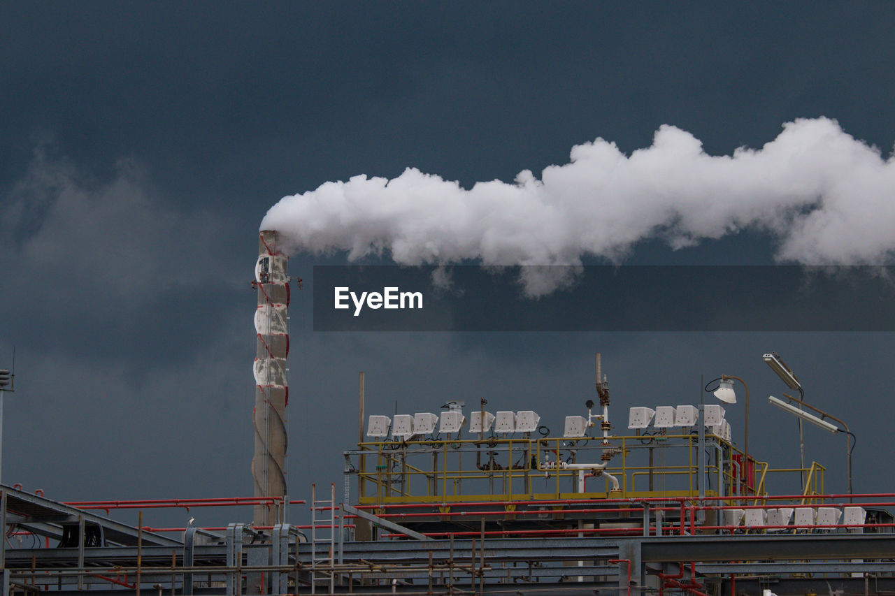Smoke emitting from factory against sky