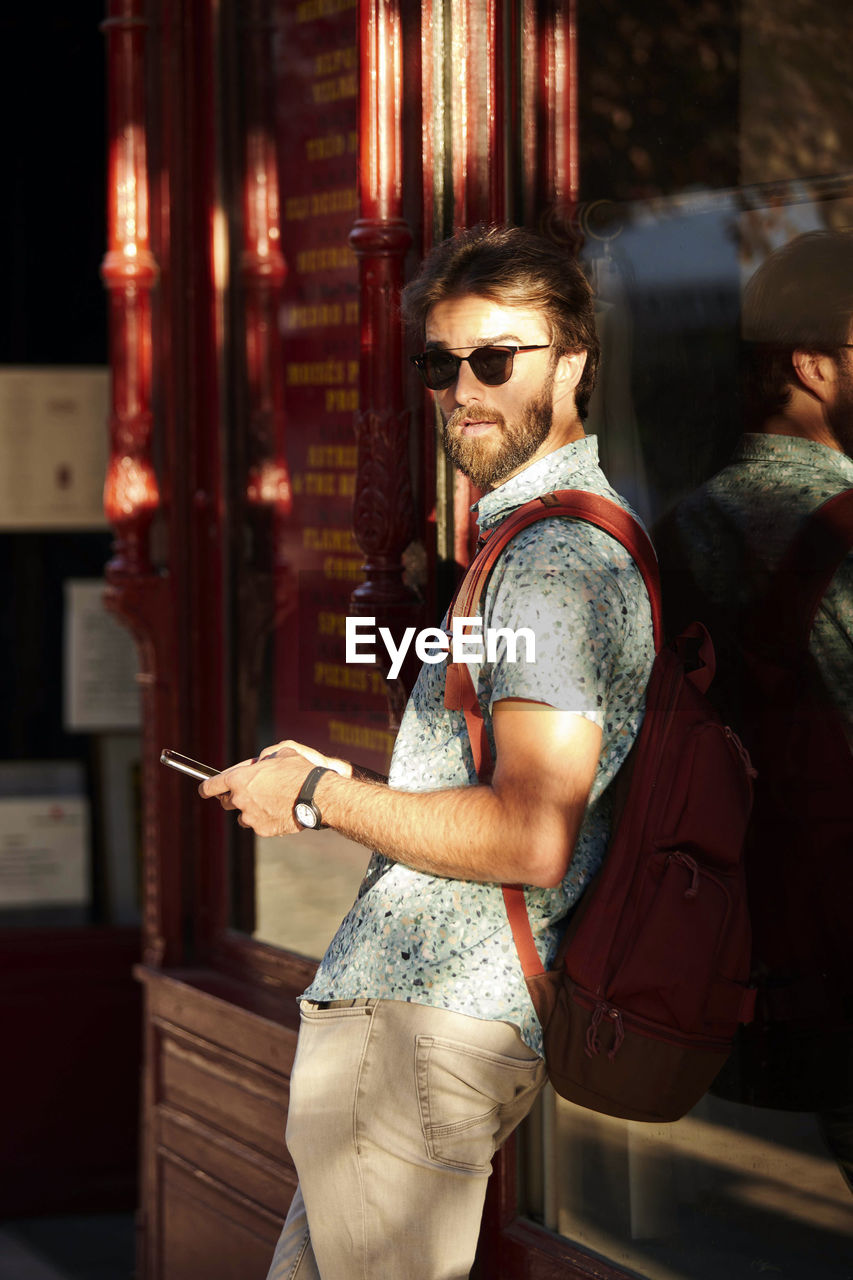 Side view of young man wearing sunglasses standing at home
