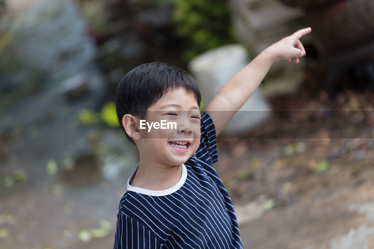 Smiling cute boy gesturing while standing outdoors