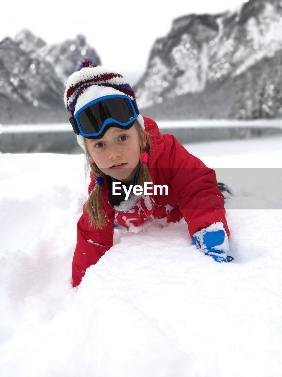 Portrait of girl lying on snow covered field