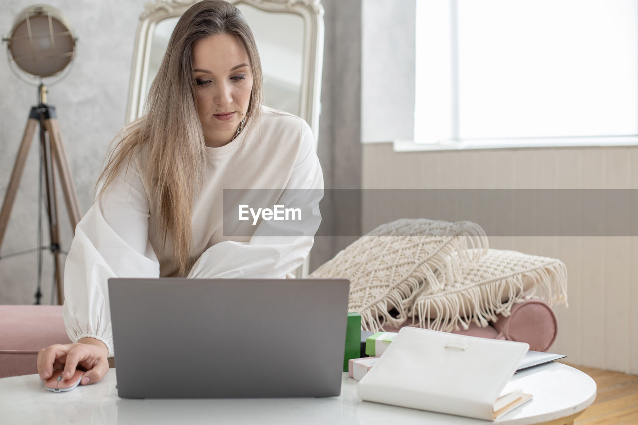 young woman using laptop while sitting on table