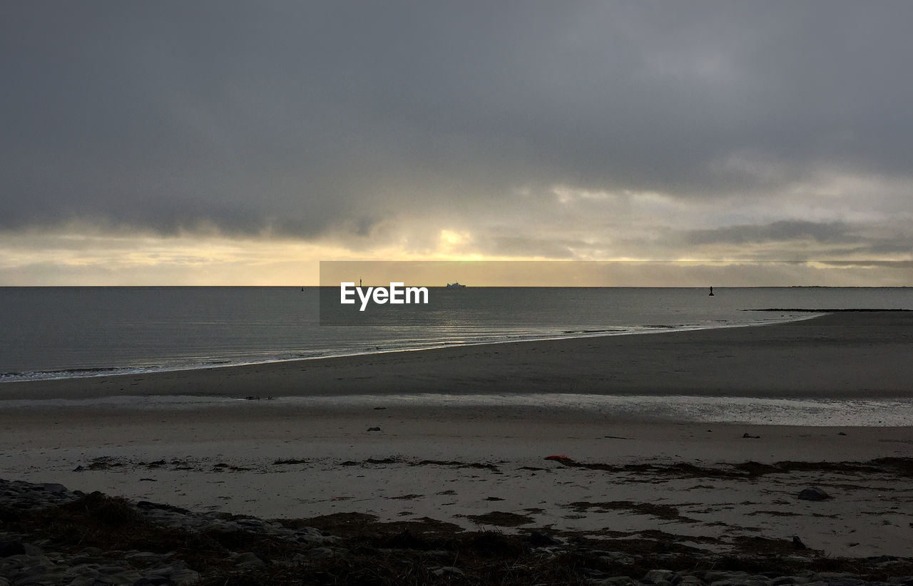 SCENIC VIEW OF SEA AGAINST CLOUDY SKY DURING SUNSET