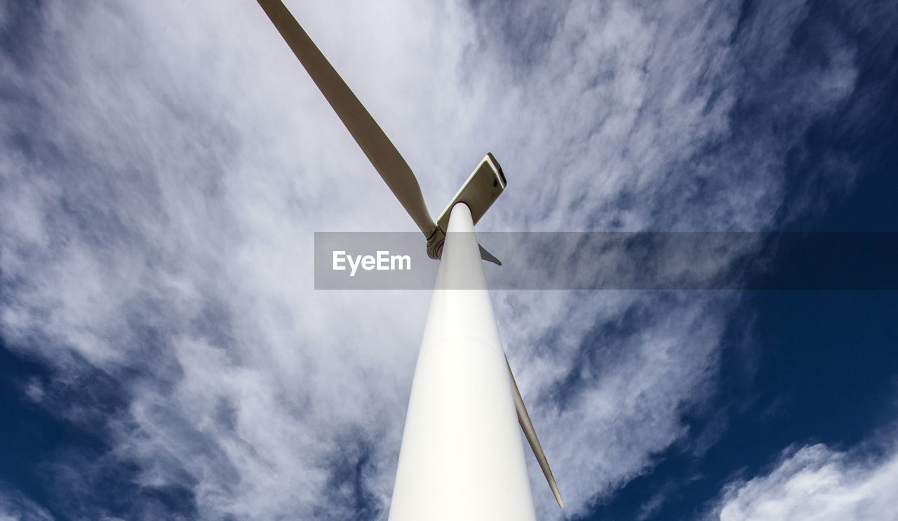 Wind turbine low angle against cloudy blue sky