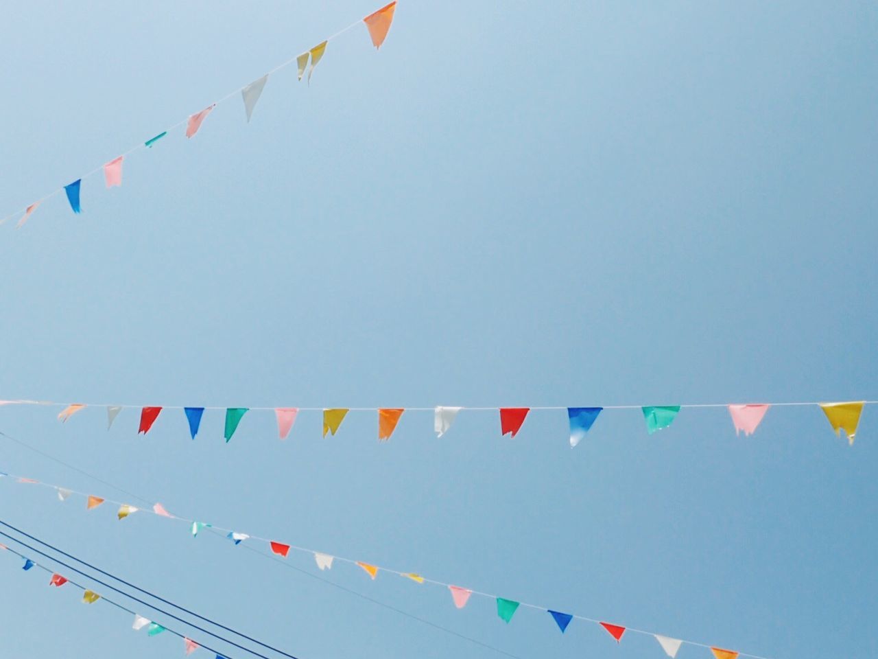 Low angle view of colorful buntings against clear blue sky