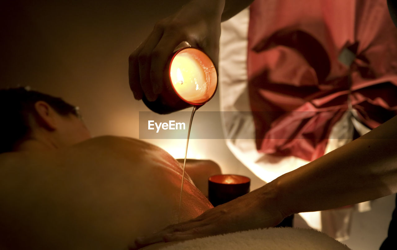 CLOSE-UP OF WOMAN HOLDING HANDS WITH ORANGE LIGHTS