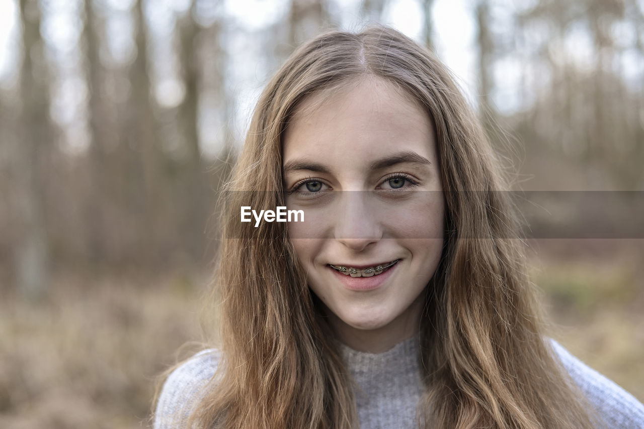 Close-up portrait of smiling teenage girl in forest