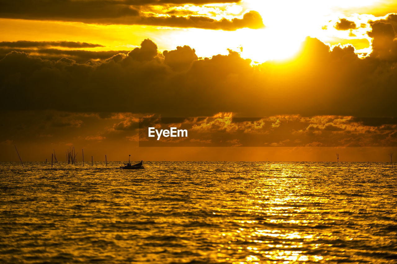 Scenic view of sea against dramatic sky during sunset