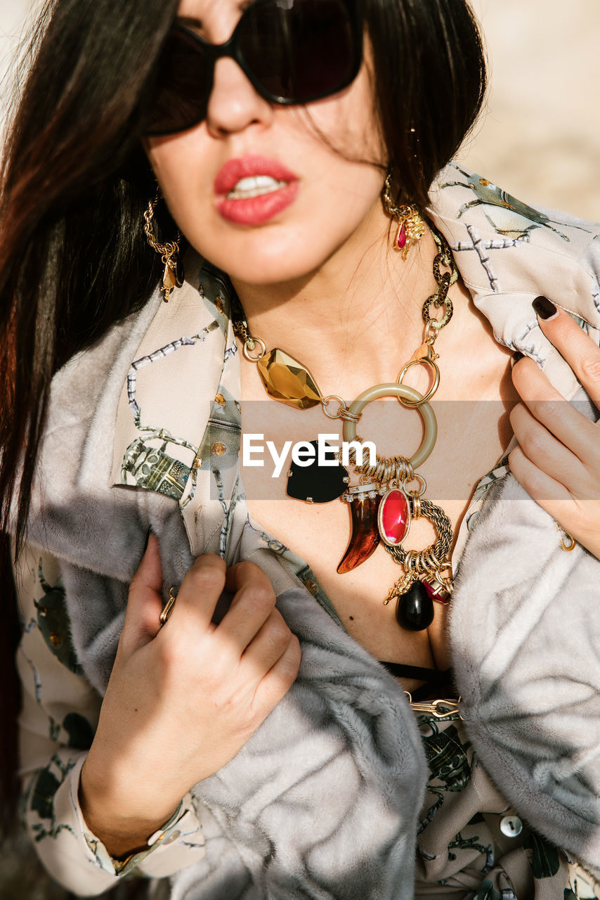 Closeup of young woman wearing sunglasses and jewelry