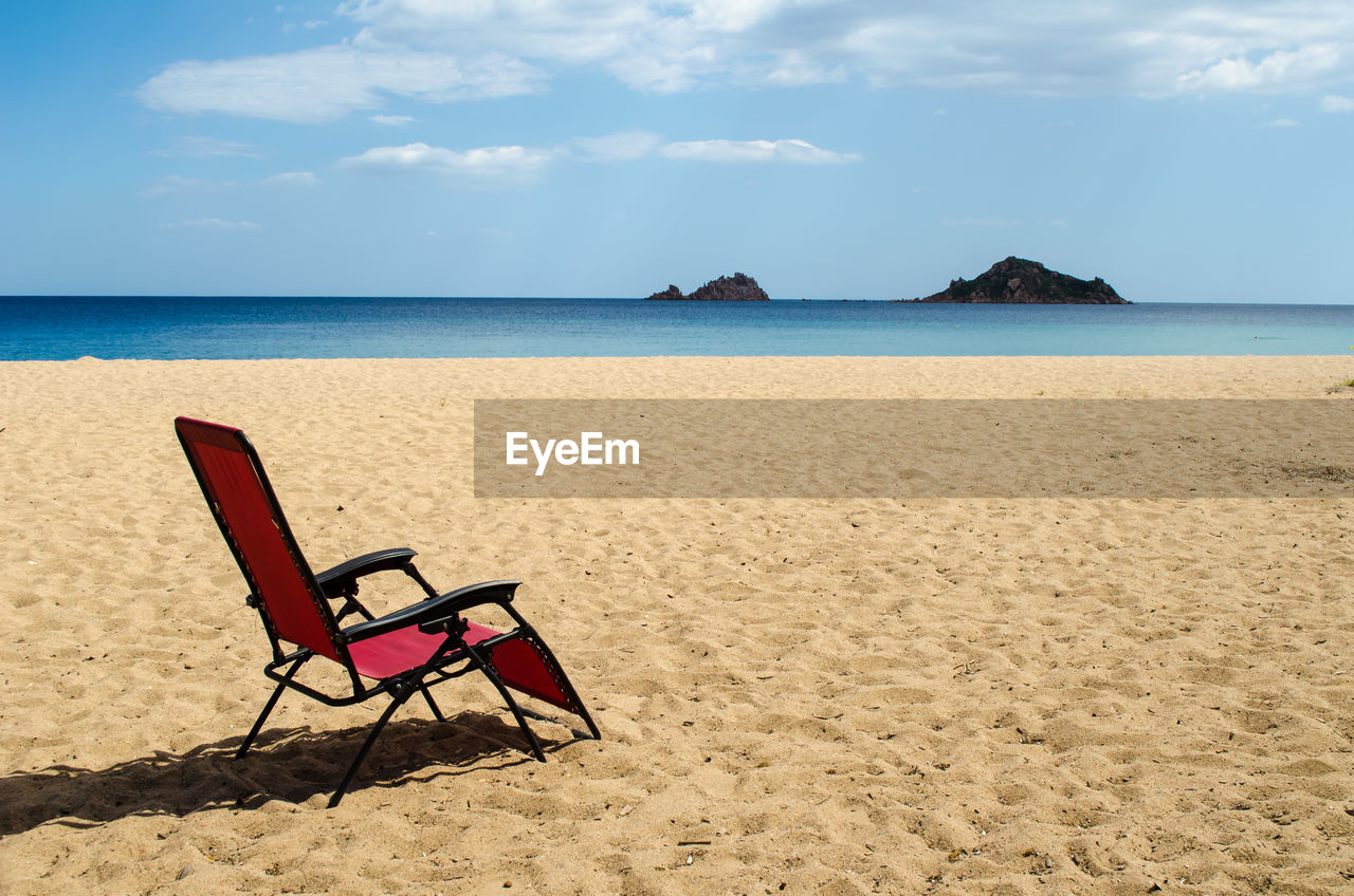 Empty chair at beach against sky