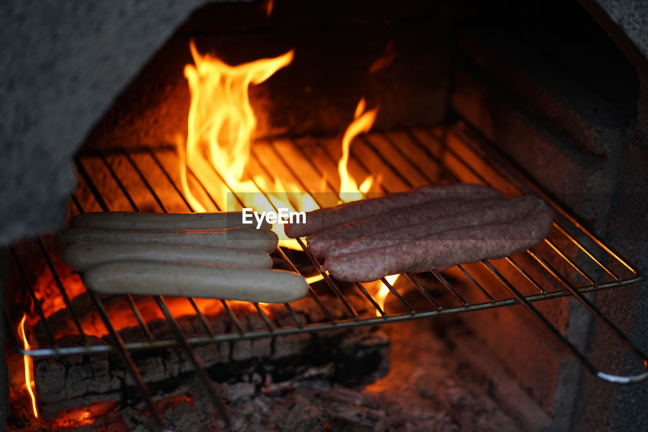 Flipping original thuringian sausages partly in natural casings on an outdoor open flame barbeque g