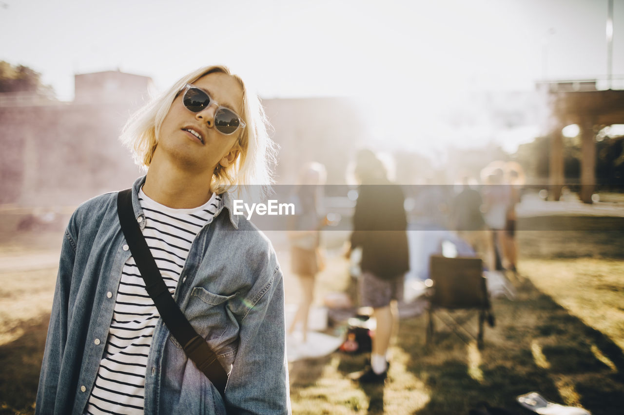 Portrait of young confident man wearing sunglasses standing in music festival