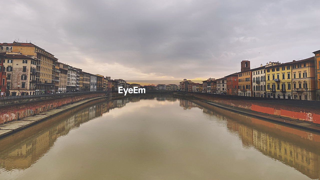 BRIDGE OVER RIVER AMIDST BUILDINGS AGAINST SKY