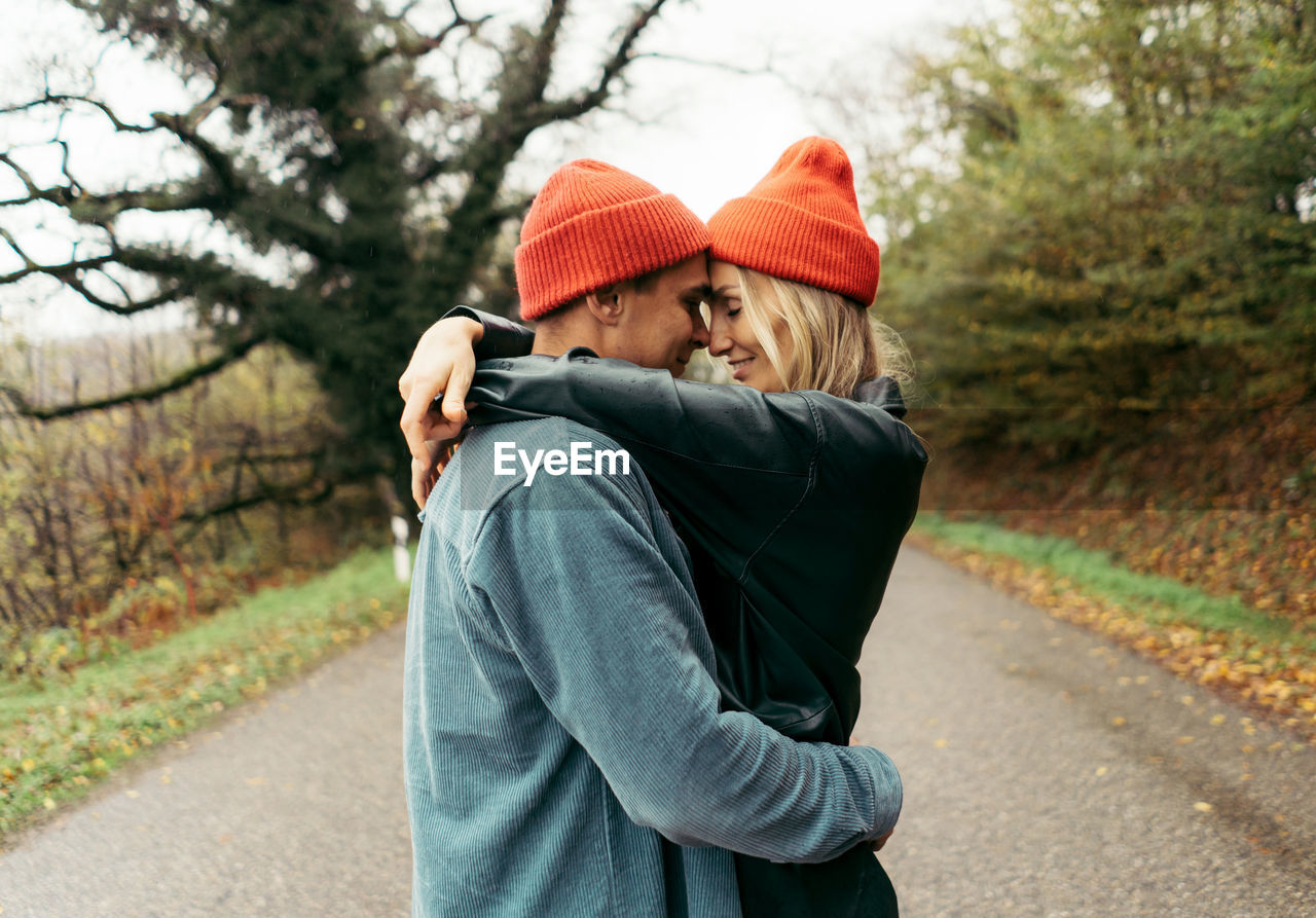 A young man and woman in love are hugging while standing on the road.