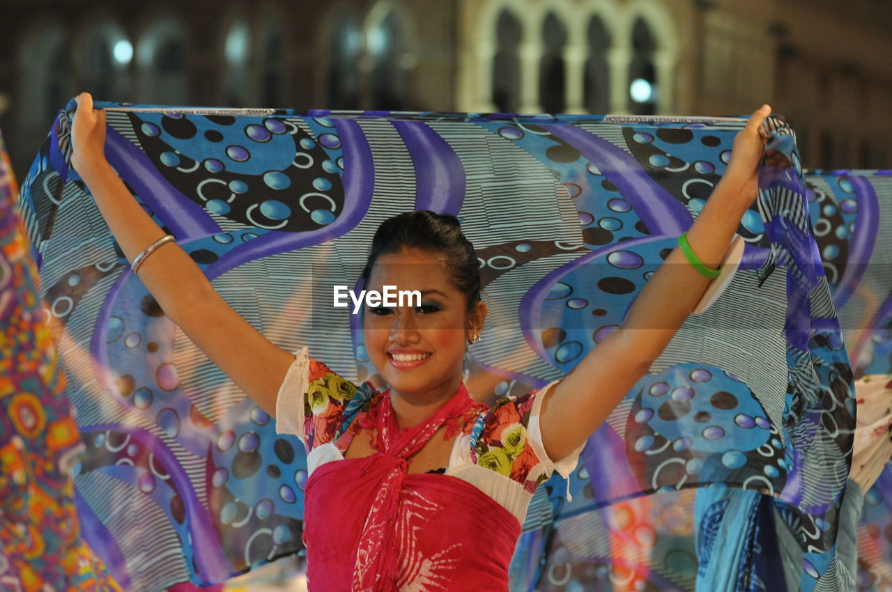 Smiling artist performing traditional dance with scarf during carnival