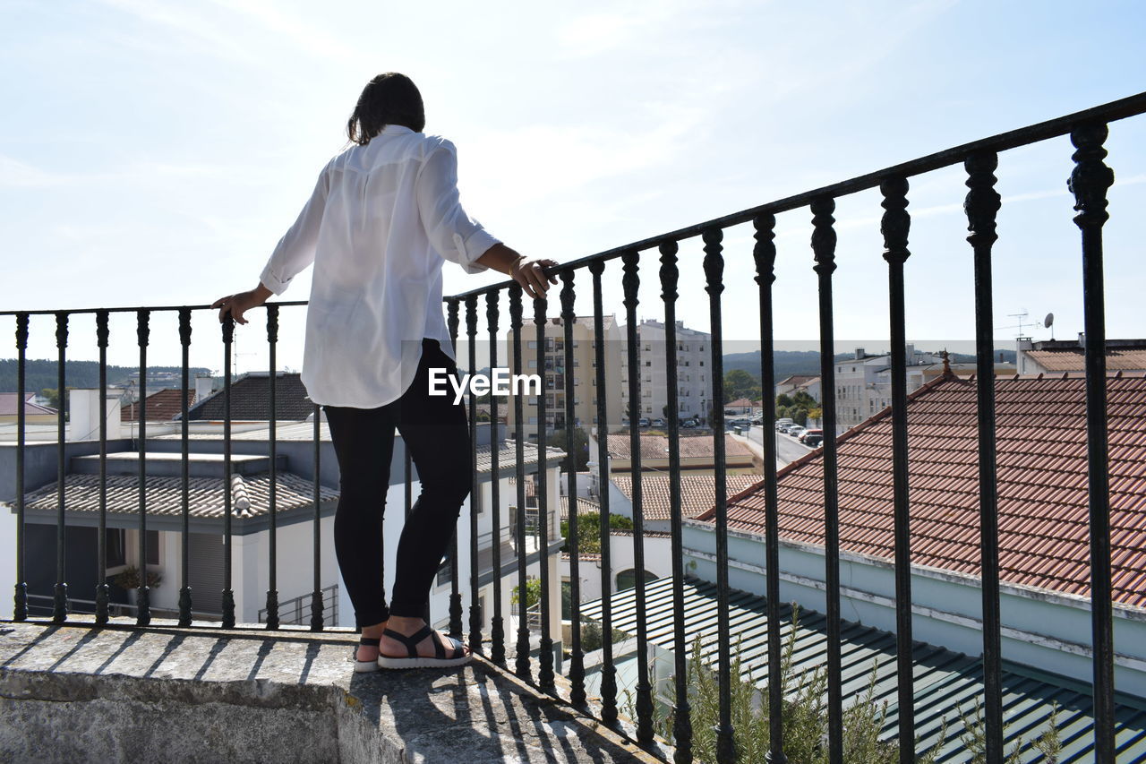 REAR VIEW OF MAN STANDING ON RAILING